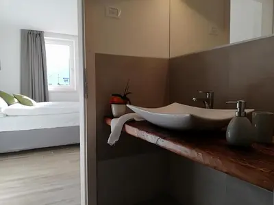 a bathroom with a large sink and a bed at Casa Lassù in Carano