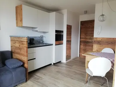 a kitchen with white cabinets and a table and chairs at Casa Lassù in Carano
