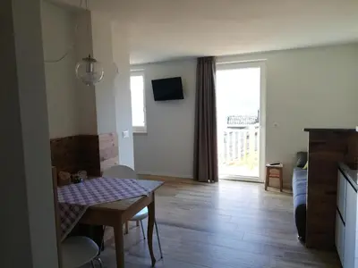 a living room with a table and a room with a window at Casa Lassù in Carano