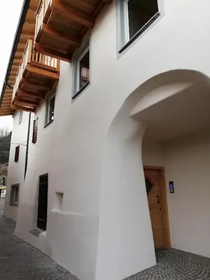 a building with an archway and a wooden door at Casa Lassù in Carano