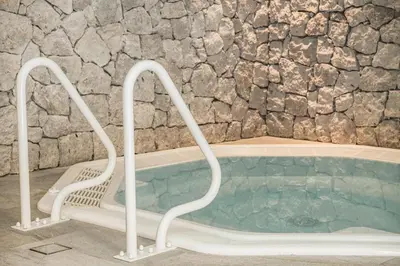 a hot tub in a room with a stone wall at Residence Altea in Ortisei
