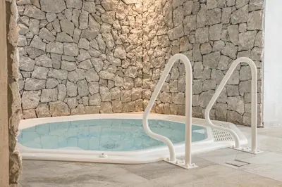 a bath tub in a room with a stone wall at Residence Altea in Ortisei