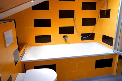 a bathroom with a toilet and a yellow tile wall at Apartment Luam - Alpstay in Naturno
