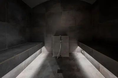 a dark room with two benches and a shower at CHALET NORA in San Vigilio Di Marebbe