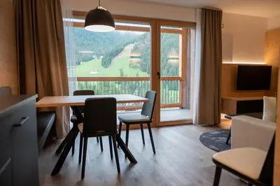 a living room with a table and chairs and a large window at CHALET NORA in San Vigilio Di Marebbe