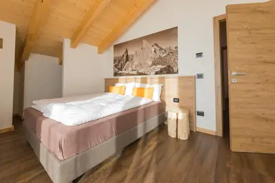 a bedroom with a bed and a painting on the wall at Latemar Fiemme Apartments in Tesero