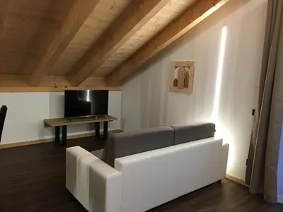 a living room with a white couch and a table at Latemar Fiemme Apartments in Tesero