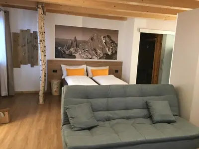 a living room with a couch and a bed at Latemar Fiemme Apartments in Tesero