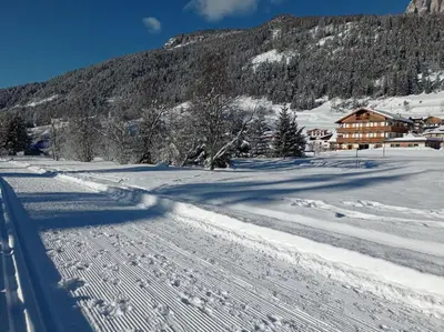 a snow covered road in front of a mountain at Residence Colibrì in Pozza di Fassa