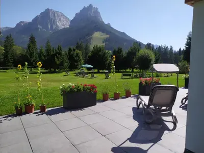 a chair sitting on a patio with mountains in the background at Residence Colibrì in Pozza di Fassa