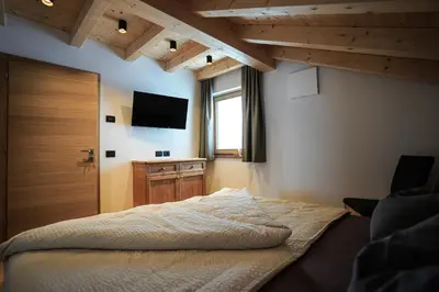 a bedroom with two beds and a flat screen tv at Lüch de Crusteles in La Valle