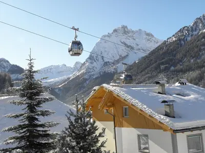 a ski lift over a house with a snow covered mountain at La casa! in Vigo di Fassa