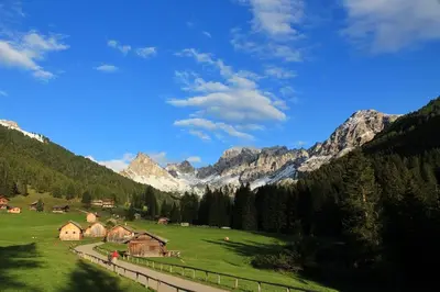 a green field with houses and mountains in the background at La casa! in Vigo di Fassa