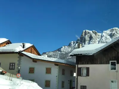 a building with snow on the roof with a mountain in the background at La casa! in Vigo di Fassa
