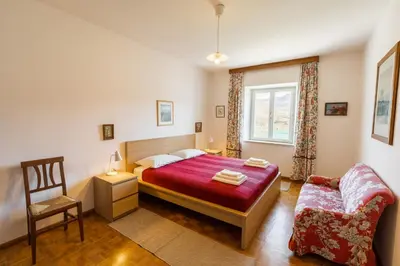 a bedroom with a bed and a chair and a window at Arzenhof, Baron Di Pauli in Caldaro