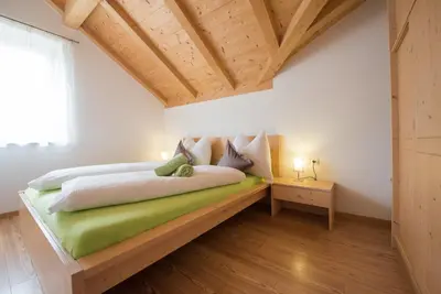 a bedroom with a bed in a room with wooden ceilings at Schwarzhaus in Monticolo