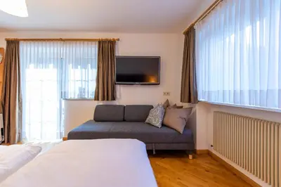 a hotel room with a couch and a tv at Apartment Belvedere in Selva di Val Gardena