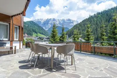 a patio with a table and chairs on a balcony at Apartment Belvedere in Selva di Val Gardena