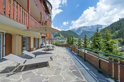a balcony of a hotel with chairs and an umbrella at Apartment Belvedere in Selva di Val Gardena