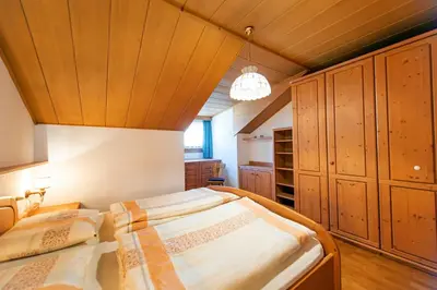 two beds in a room with wooden ceilings and wooden cabinets at Apartments Sal Feur in Selva di Val Gardena
