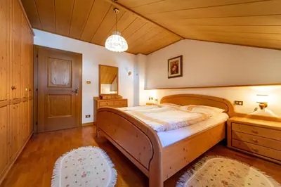 a bedroom with a wooden bed and a wooden ceiling at Apartments Sal Feur in Selva di Val Gardena