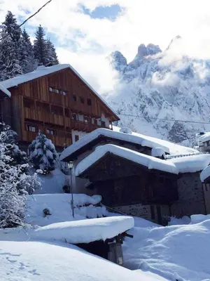 a building covered in snow with mountains in the background at Studio Ebi Vacation - Alleghe - Monte Civetta in Alleghe