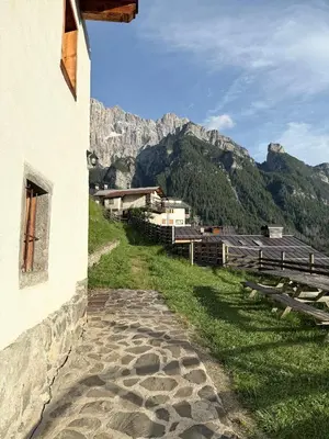 a path next to a building with mountains in the background at Studio Ebi Vacation - Alleghe - Monte Civetta in Alleghe