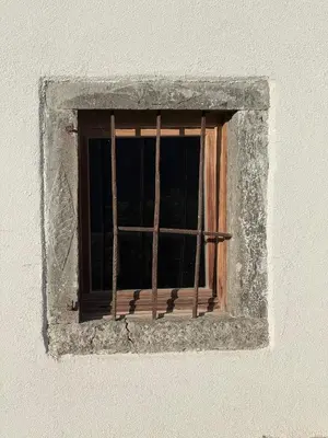 a window with bars on a white wall at Studio Ebi Vacation - Alleghe - Monte Civetta in Alleghe