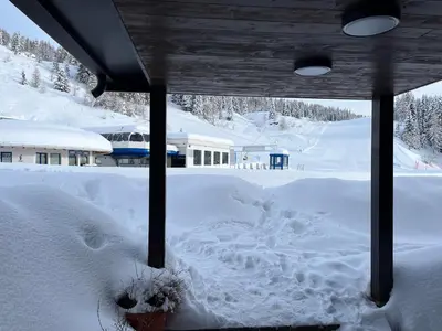 a yard covered in snow with a building in the background at Casa Mammolo Falcade in Falcade