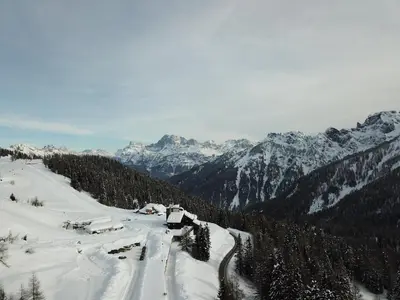 a snow covered mountain with trees and snow covered mountains at Casa Mammolo Falcade in Falcade