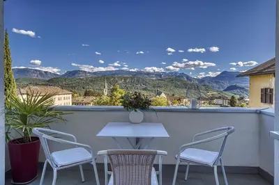 a white table and chairs on a balcony with mountains at HOMESTWENTY3 - Home two in Caldaro