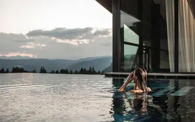 a woman laying in the water in a swimming pool at AEON Hotel - adults only Bed & Breakfast in Soprabolzano