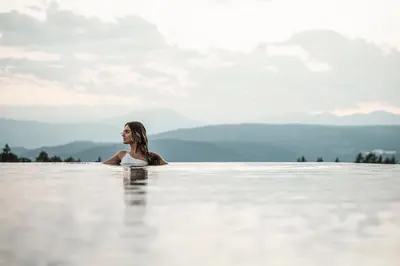 a woman in a infinity pool with mountains in the background at AEON Hotel - adults only Bed & Breakfast in Soprabolzano
