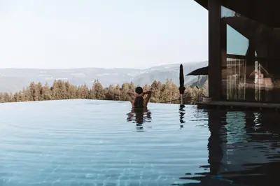 a person standing in the water in a swimming pool at AEON Hotel - adults only Bed & Breakfast in Soprabolzano