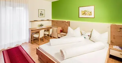 a small room with two beds and a desk at Residence Preyhof in Caldaro