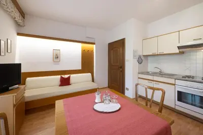 a kitchen and a living room with a table and a couch at Residence Preyhof in Caldaro