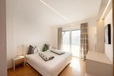 a white bedroom with a white couch and a window at Residence Preyhof in Caldaro