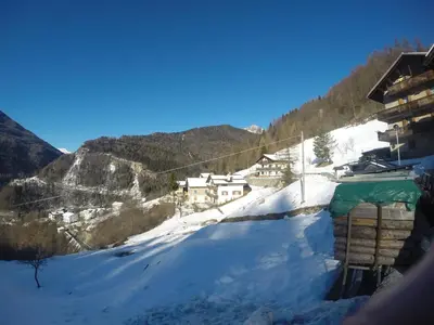 a snow covered hill with houses and a mountain at Casa Alpina in Cencenighe