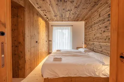 a bedroom with a large bed with a wooden wall at Casa del Lupo in Cortina dʼAmpezzo