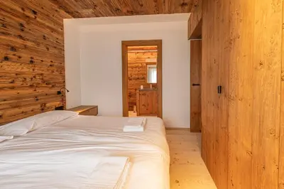 a bedroom with a bed and a wooden wall at Casa del Lupo in Cortina dʼAmpezzo
