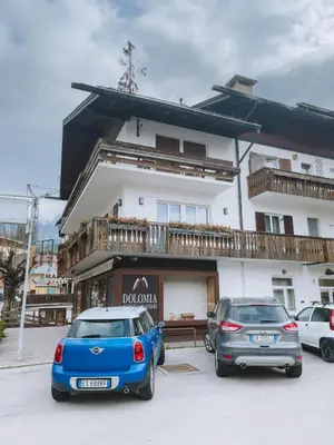 two cars parked in a parking lot in front of a building at Casa del Lupo in Cortina dʼAmpezzo