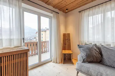 a living room with a couch and a large window at Casa del Lupo in Cortina dʼAmpezzo