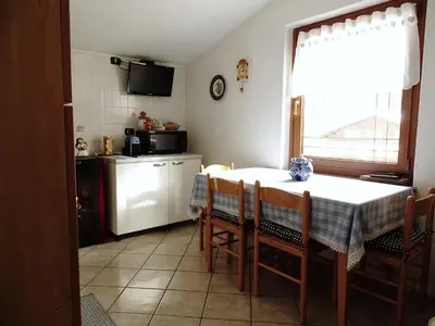 a kitchen with a table and chairs and a kitchen with a window at Casa Minela in Falcade