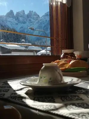 a table with a plate and a cup and a window at Casa Minela in Falcade