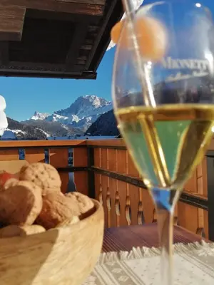 a glass of wine sitting on a table with a basket of bread at Casa Minela in Falcade