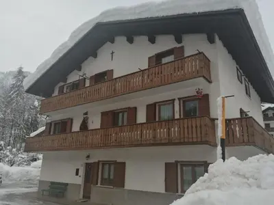 a building with a balcony in the snow at Casa Minela in Falcade