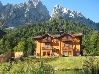a large house with mountains in the background at Hotel Chalet Giasenei in Sagron Mis