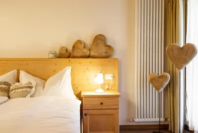 a bedroom with a bed and two hearts on the wall at Hotel Chalet Giasenei in Sagron Mis