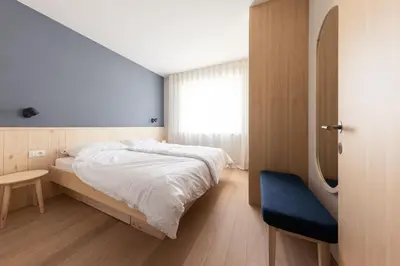 a bedroom with a bed and a blue chair at Mondschein Apartments in Lana