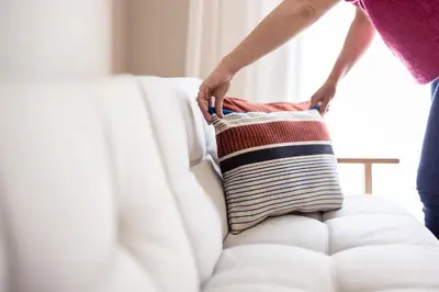 a woman holding a striped pillow on a couch at Mondschein Apartments in Lana